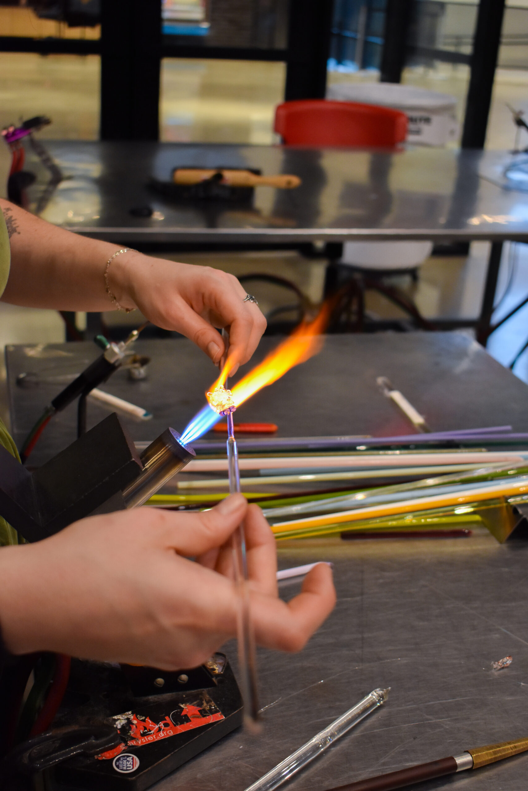 Hands working with glass in a torch flame