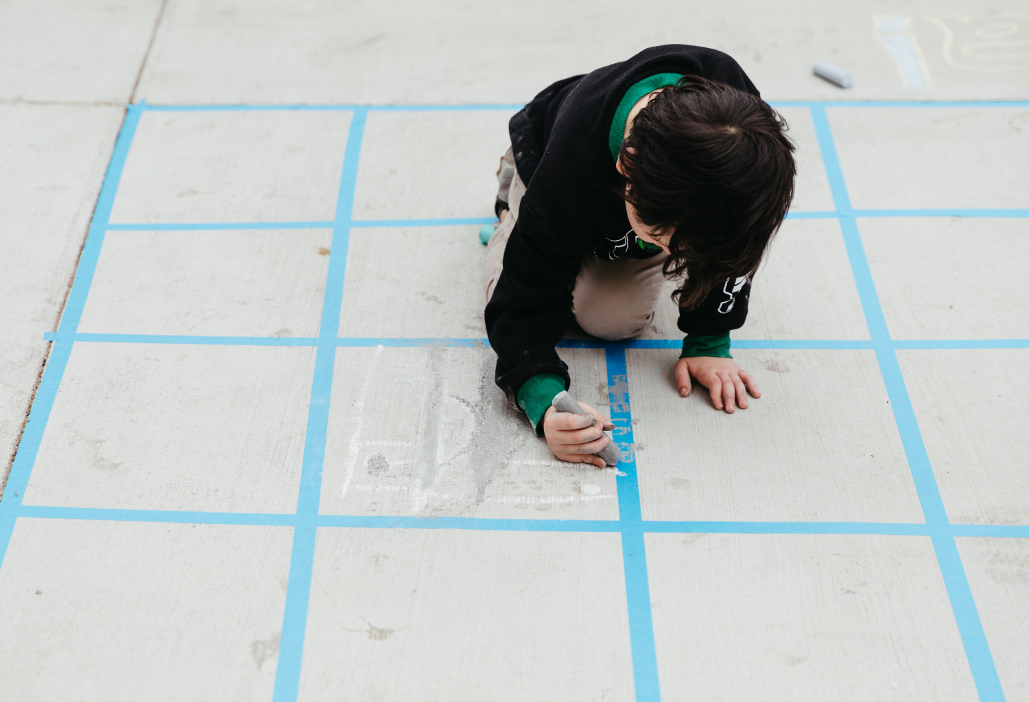 Child drawing with chalk in large grid