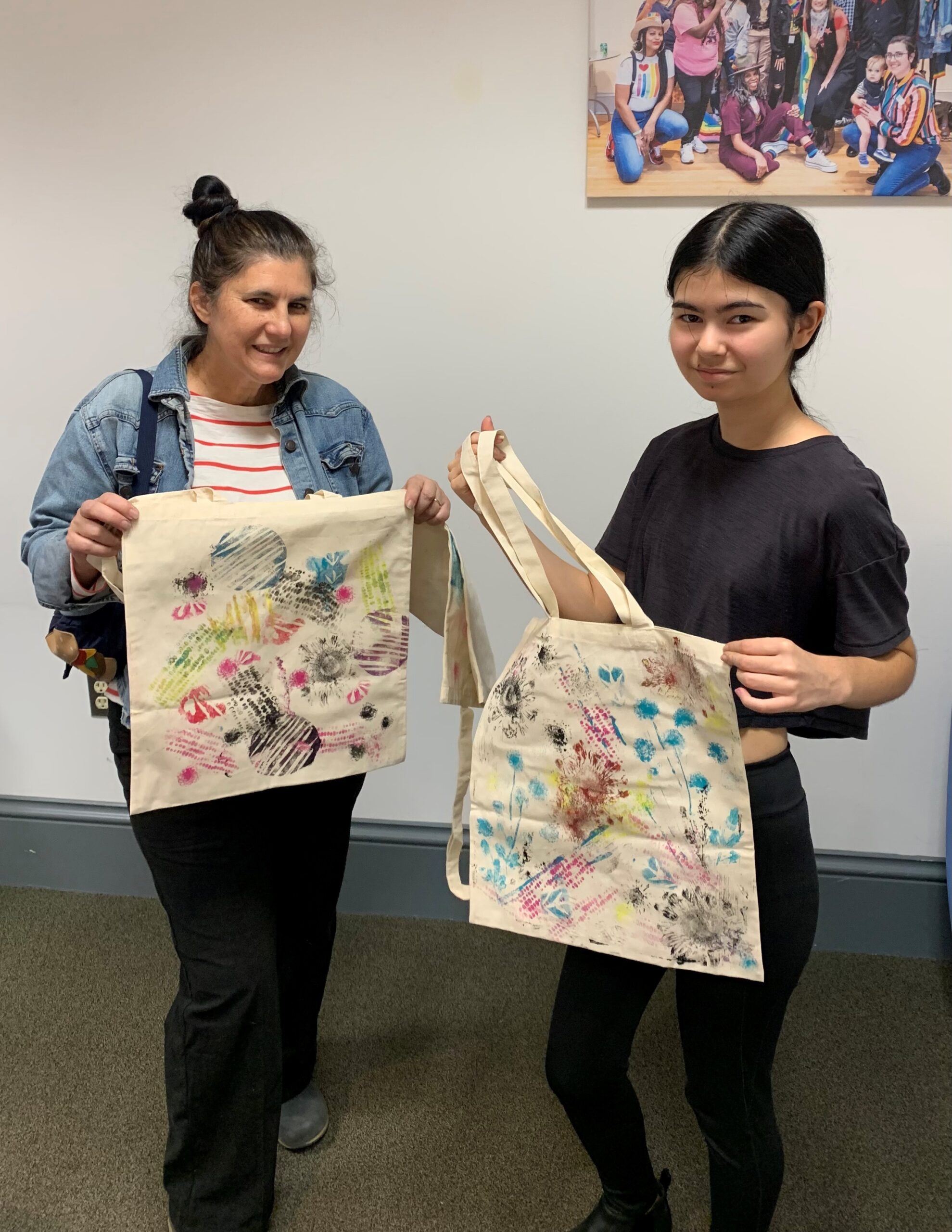 People holding up totebags they made art on