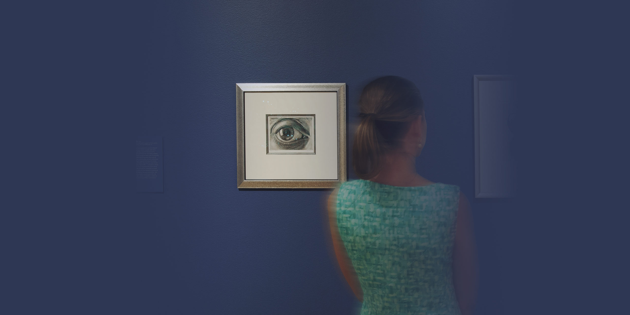 woman in green dress with back to the camera in front of a sketch of an eye