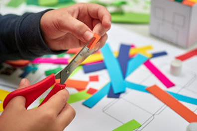 Kid cutting up paper for craft session.